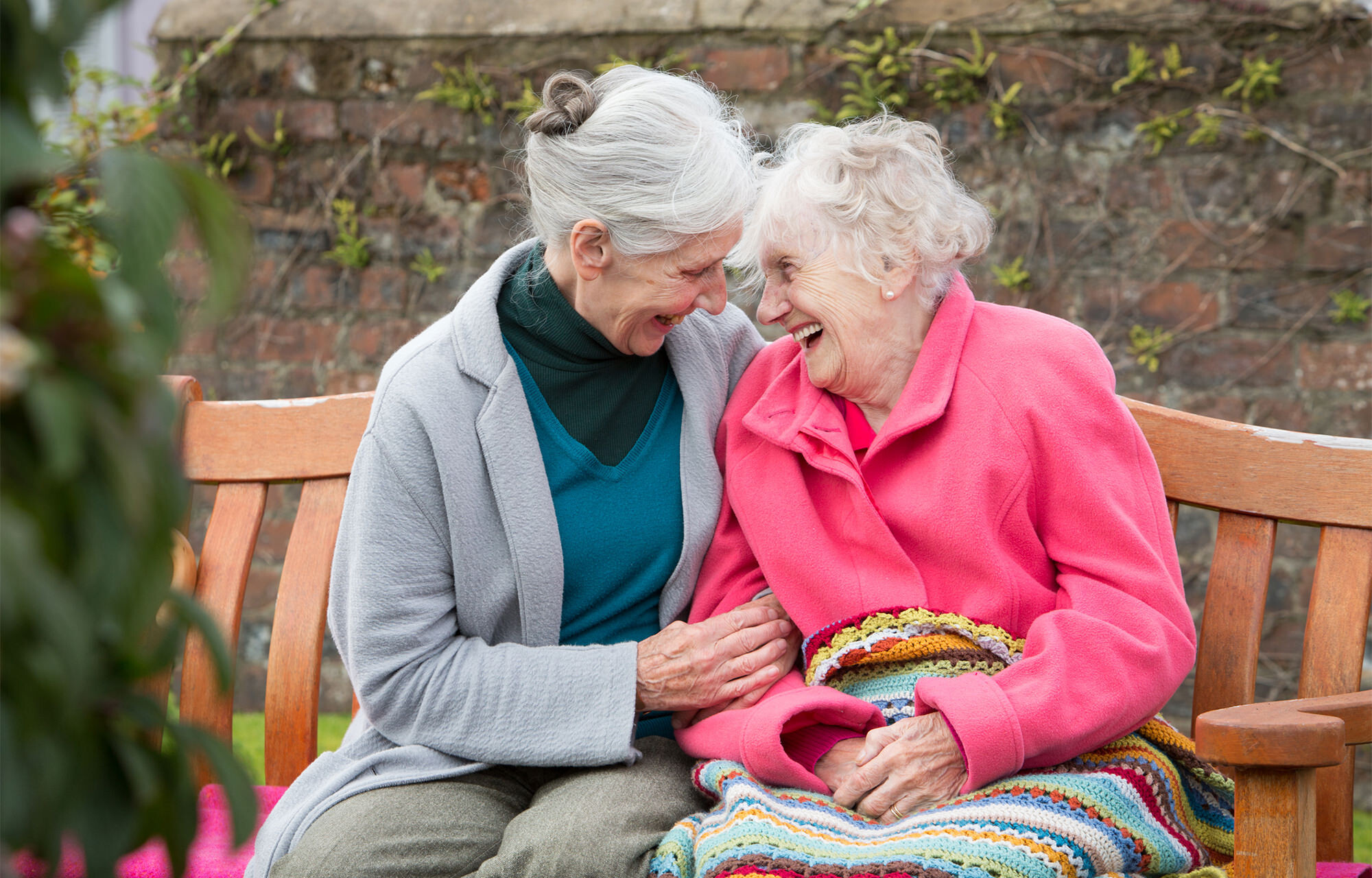 Two elderly women chatting on a bench